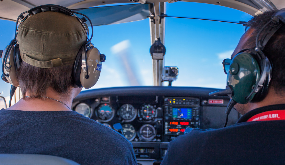 Two students in a cockpit during pilot training at flight school, practicing communication and navigation.